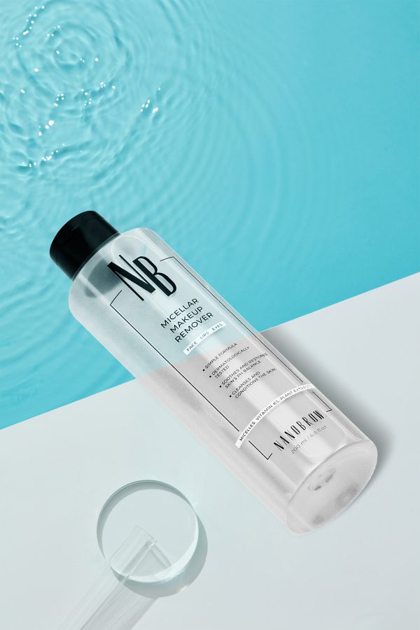 Blue cosmetic bottle on white square podium and the blue water surface with test tube. Blank label with texture for branding mock-up. Flat lay, top view.